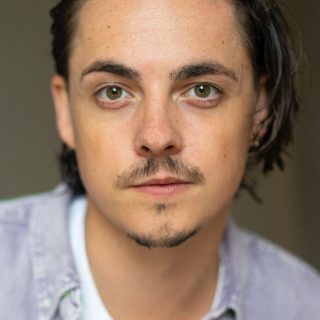 An actor with medium length brown hair and a goatee