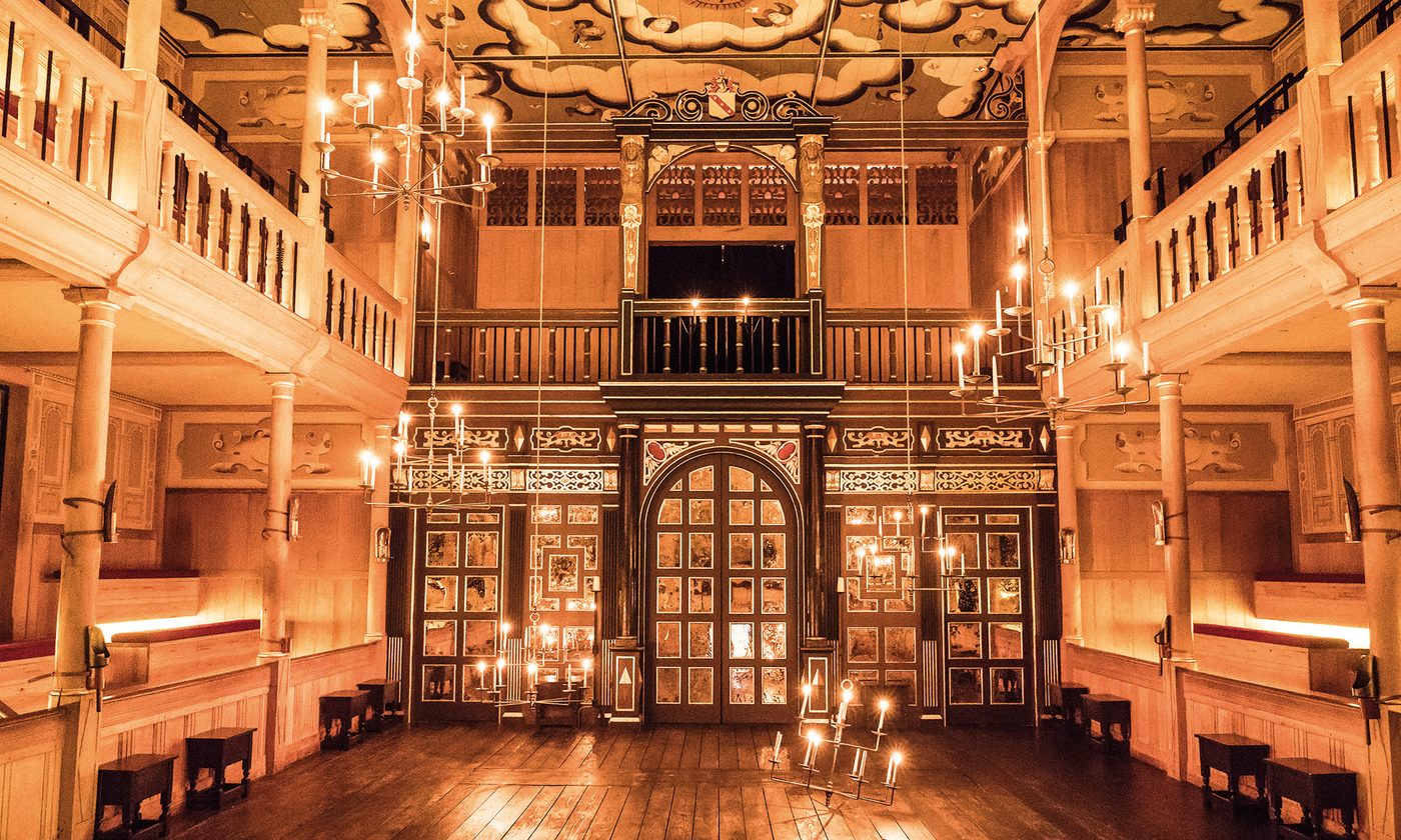 The candlelit interior of an indoor playhouse, with dark wooden panelling and a golden glow.