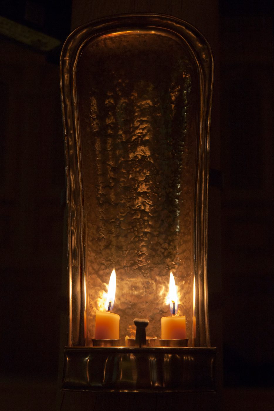 Two cream candles are lit in the darkness