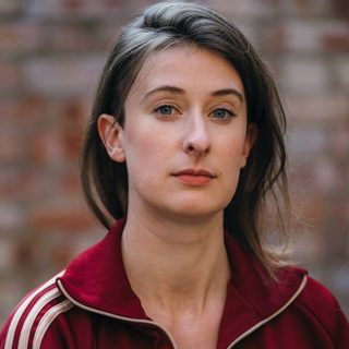 Sophie Steer wearing a red tracksuit and looking directly at the camera.