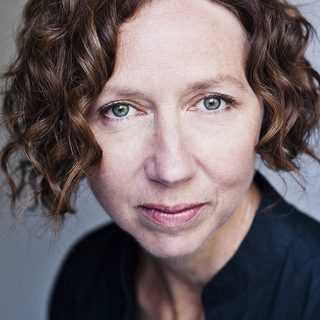 Amanda Hadingue wearing a black blouse and looking directly at the camera.