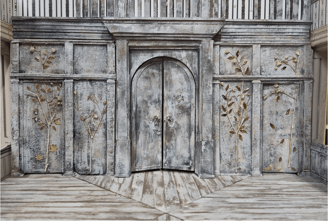 Close-up of the set design of Three Sisters on a model box. The model shows the back wall of the stage, which has been clad with silver birch and adorned with trees picked out in gold relief.